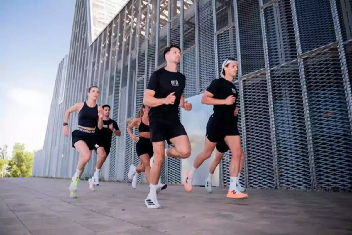 Grupo de personas corriendo juntos al aire libre junto a un edificio moderno