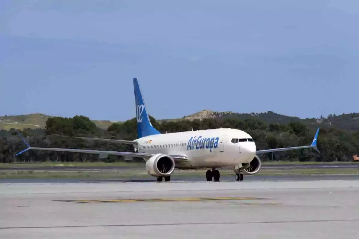Avión de Air Europa rodando por la pista de un aeropuerto con árboles y colinas al fondo