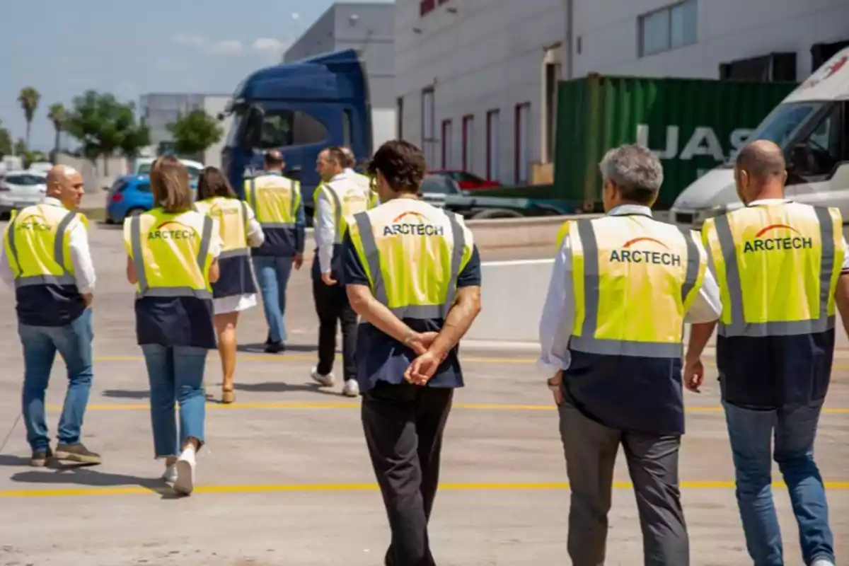 Grupo de personas con chalecos de seguridad caminando por un área industrial al aire libre