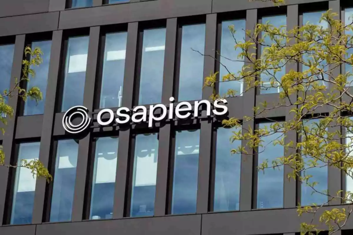 Fachada de edificio moderno con el logo de osapiens y ramas de un árbol en primer plano