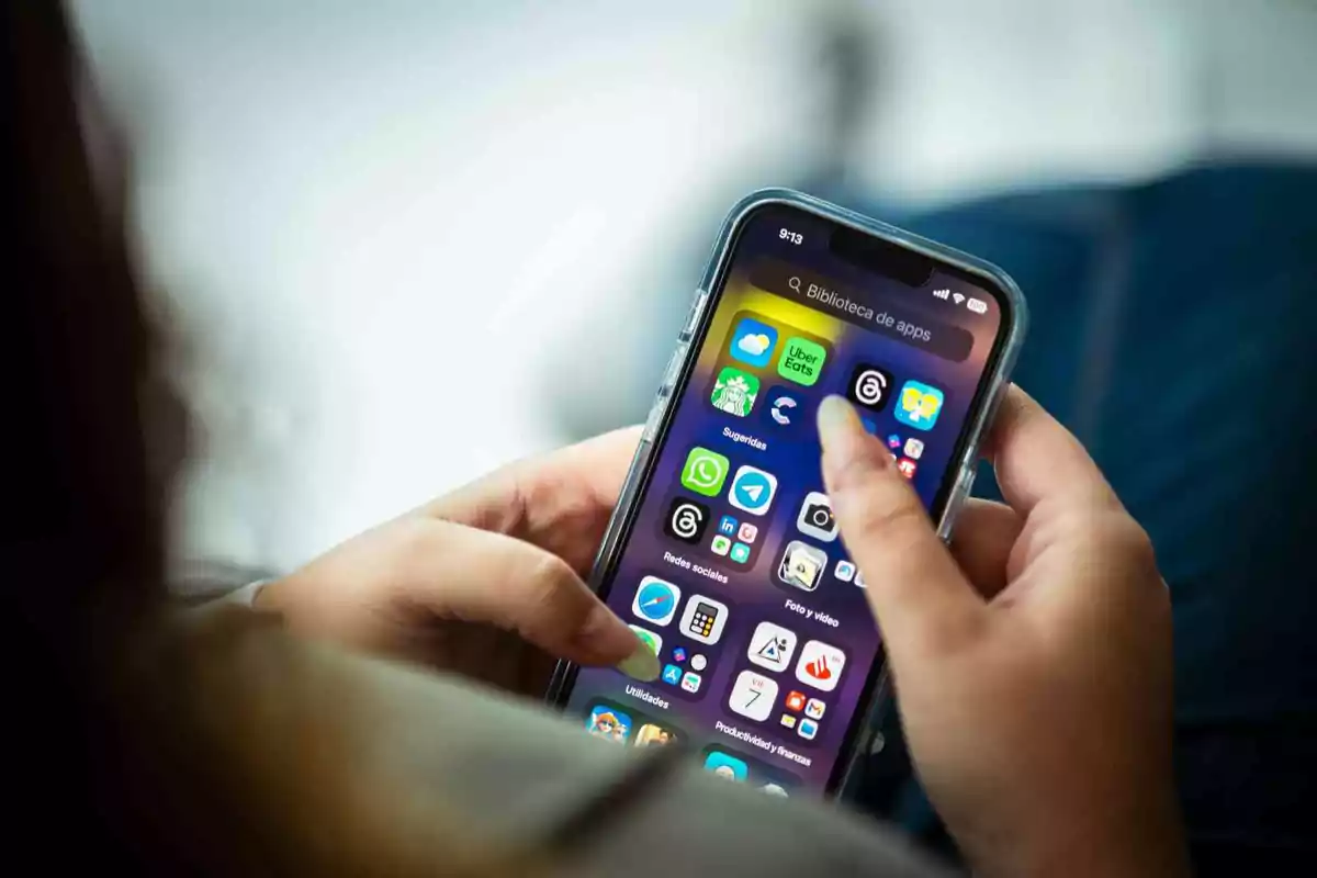 Persona usando un teléfono móvil mientras navega por la pantalla de aplicaciones
