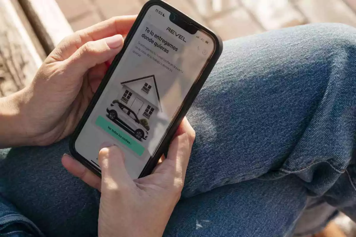 Persona usando un teléfono móvil para ver una página web de entrega de autos a domicilio mientras está sentada con jeans azules.