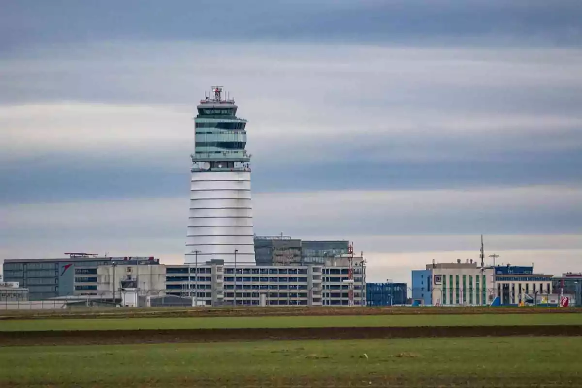 Torre de control de un aeropuerto rodeada de edificios bajo un cielo nublado Torre de control de un aeropuerto rodeada de edificios bajo un cielo nublado