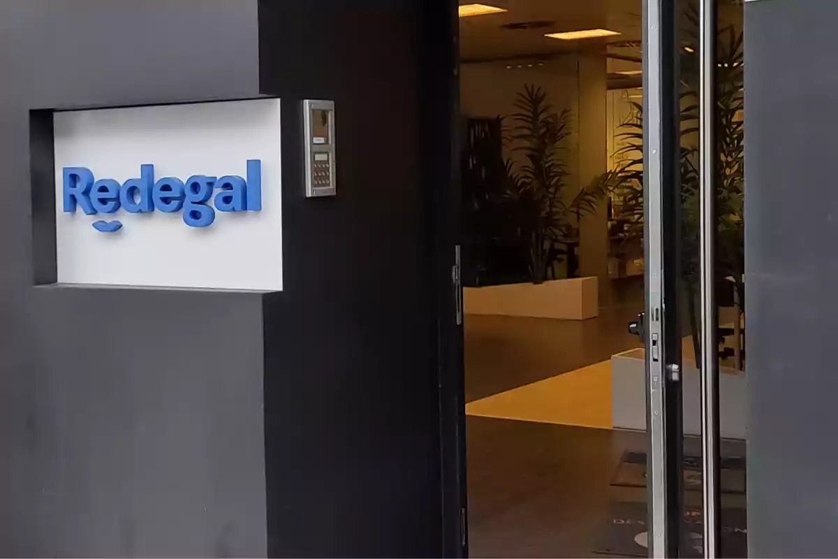 Entrada de una oficina moderna con un letrero que dice Redegal y plantas en el interior