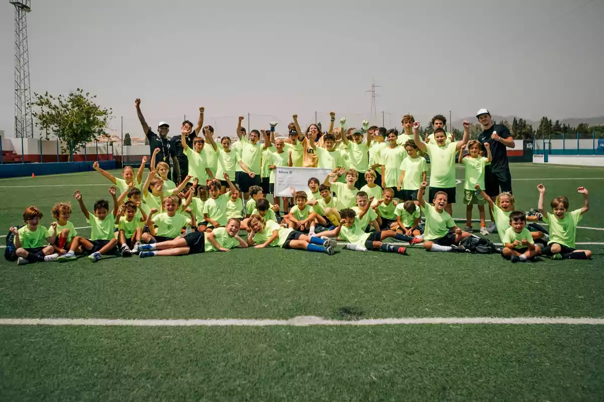 Grupo de niños y entrenadores con camisetas fosforescentes celebrando juntos en un campo de fútbol