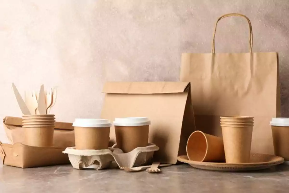 Vasos, platos, cubiertos y bolsas de papel ecológico sobre una mesa