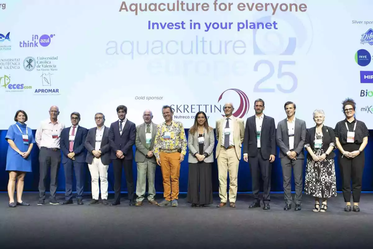 Un grupo de personas posando en el escenario de un evento de acuicultura con un fondo que muestra logotipos de patrocinadores y el lema Aquaculture for everyone Invest in your planet