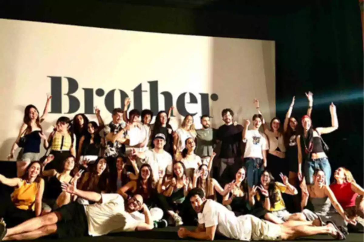 Grupo de personas posando sonrientes frente a una pantalla grande con la palabra Brother