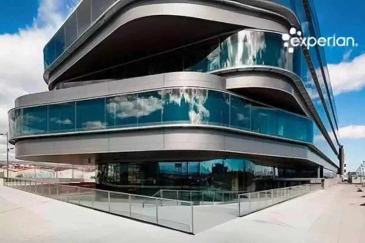 Edificio moderno de cristal y metal con reflejo de nubes en las ventanas y el logo de Experian en la esquina superior derecha