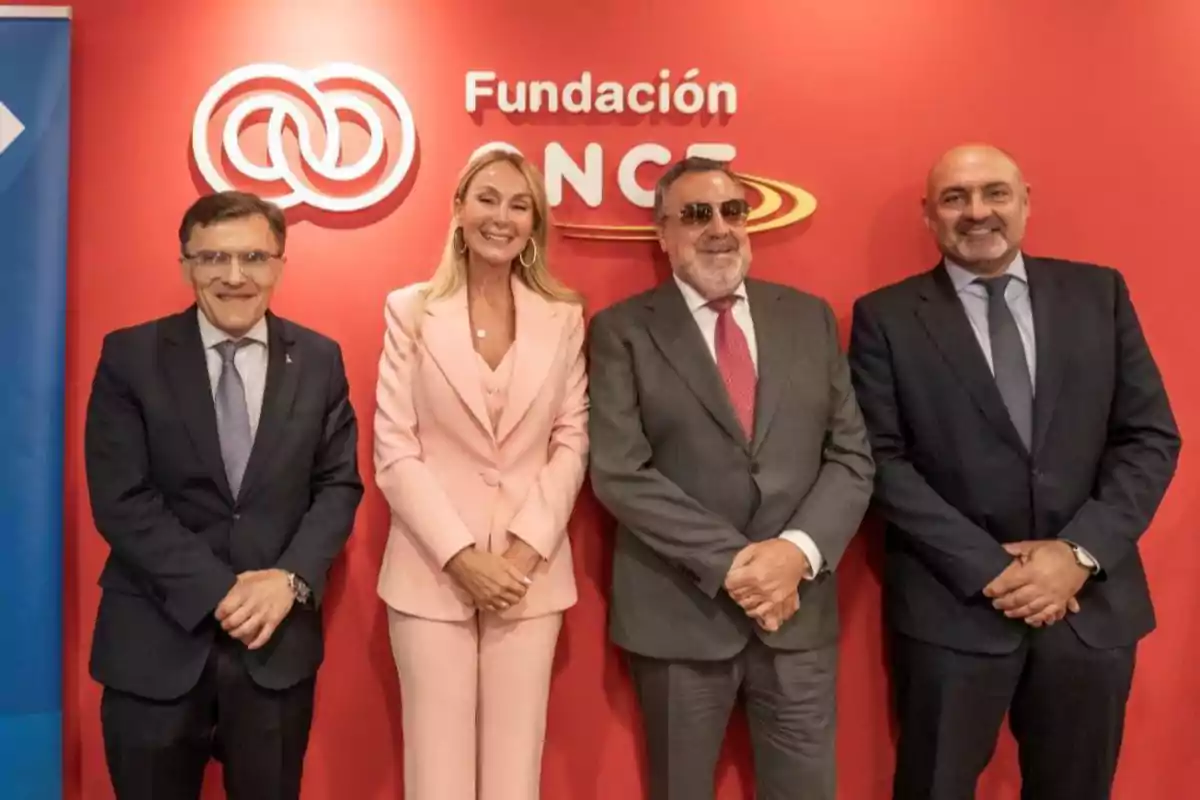 Cuatro personas posan sonrientes frente a una pared roja con el logo y el nombre de Fundación ONCE