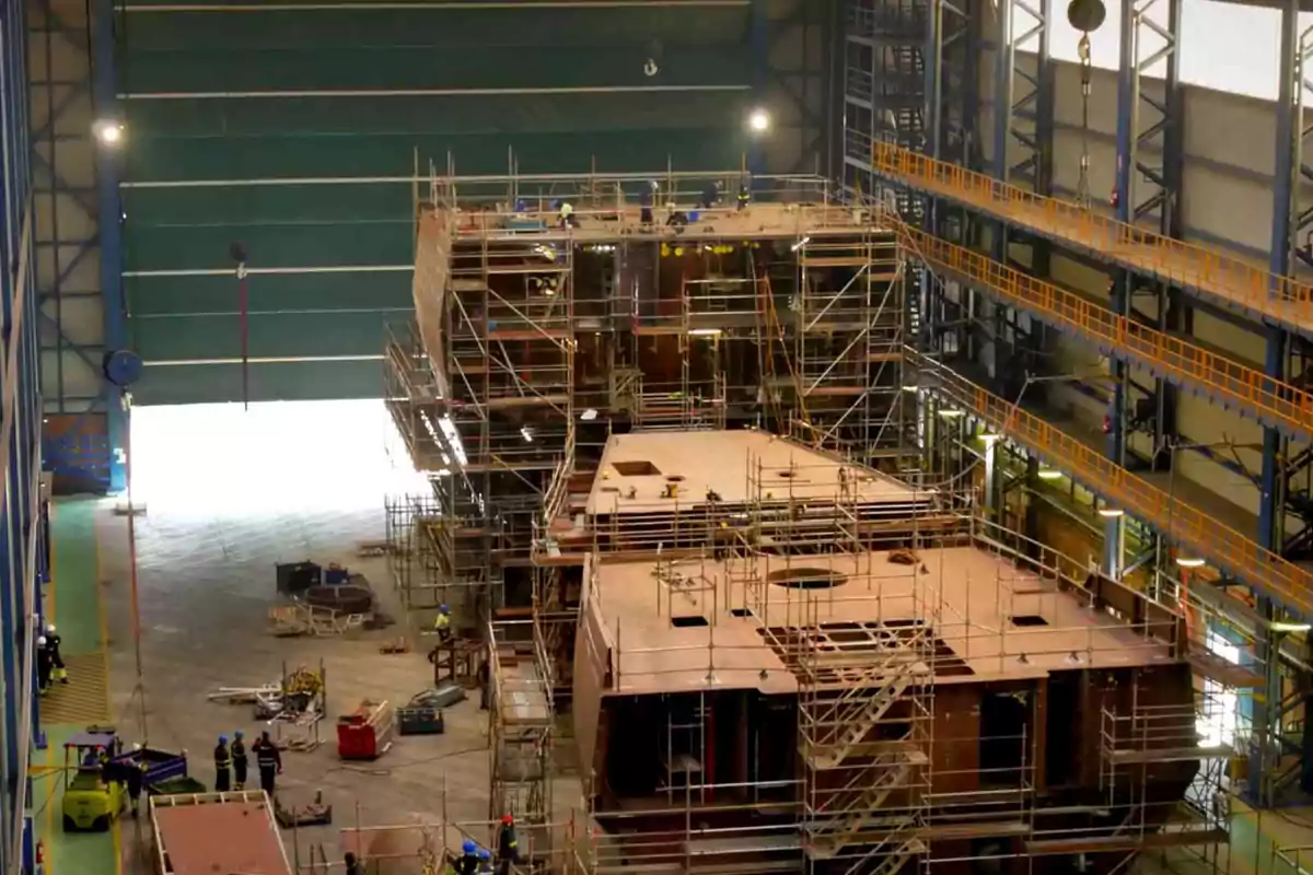 Construcción de un barco en un astillero con andamios y trabajadores alrededor de la estructura