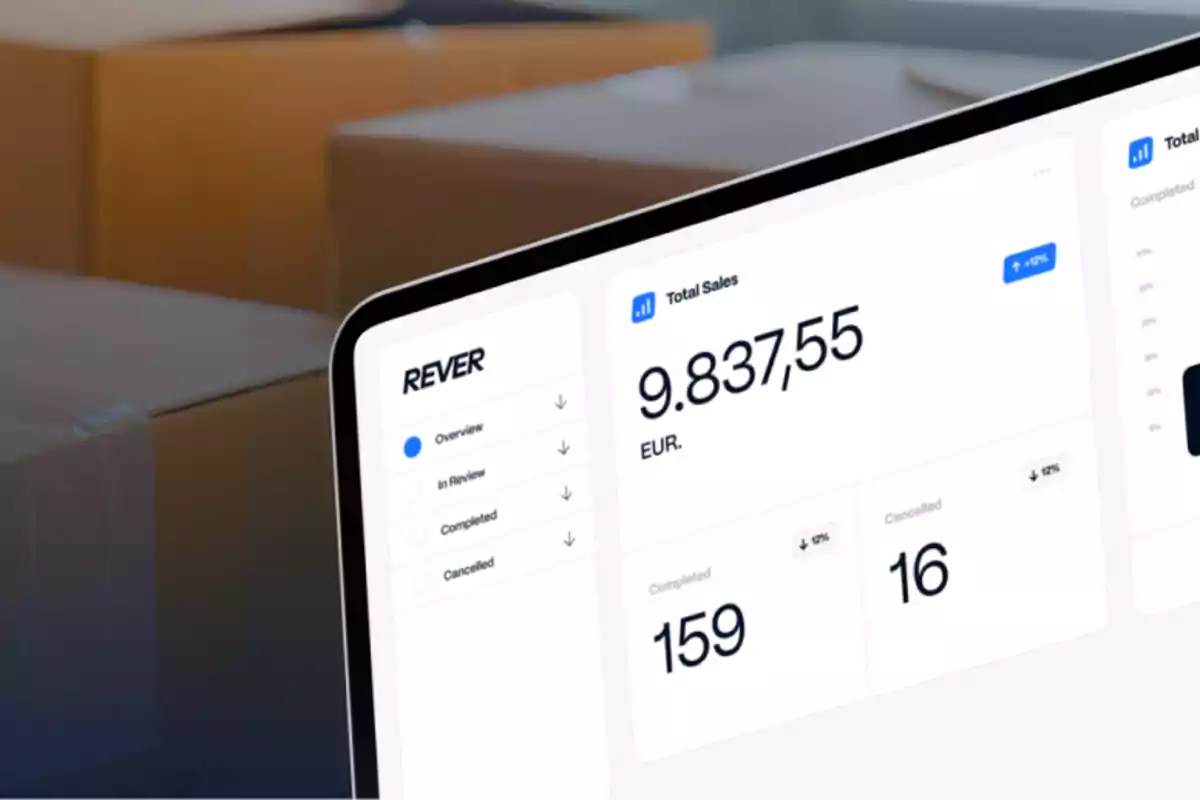 Pantalla de computadora portátil mostrando un panel de control de ventas con cajas de cartón desenfocadas al fondo Pantalla de computadora portátil mostrando un panel de control de ventas con cajas de cartón desenfocadas al fondo