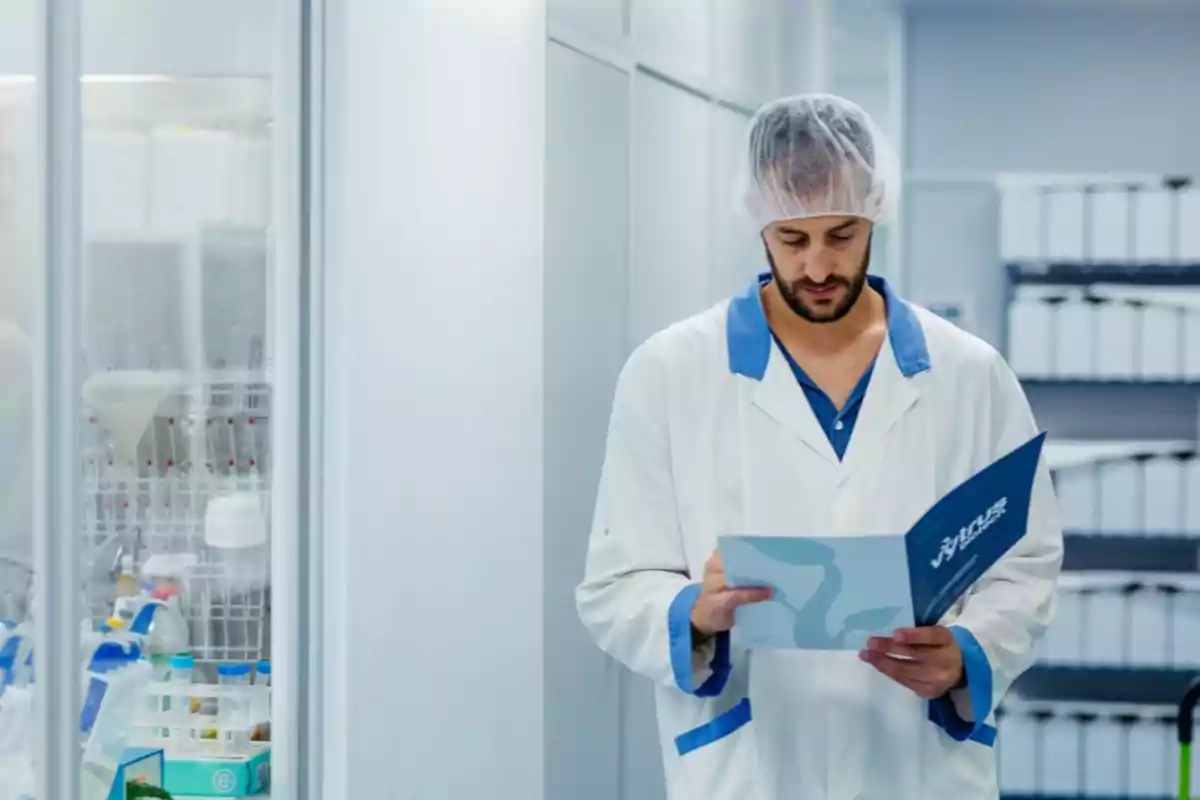 Hombre con bata y gorro de laboratorio revisando documentos en un pasillo de laboratorio Hombre con bata y gorro de laboratorio revisando documentos en un pasillo de laboratorio