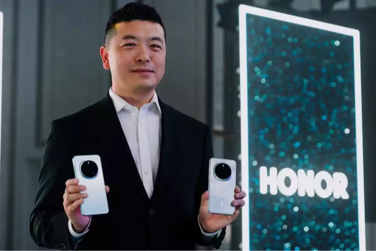 Hombre con traje sosteniendo dos teléfonos inteligentes frente a un cartel iluminado con la palabra HONOR Hombre con traje sosteniendo dos teléfonos inteligentes frente a un cartel iluminado con la palabra HONOR