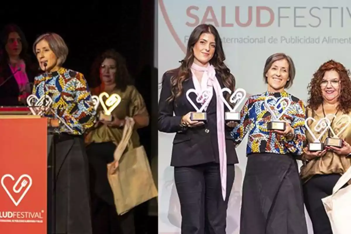 Tres mujeres posan sonrientes en un escenario sosteniendo trofeos en forma de corazón durante un evento de premiación llamado Salud Festival