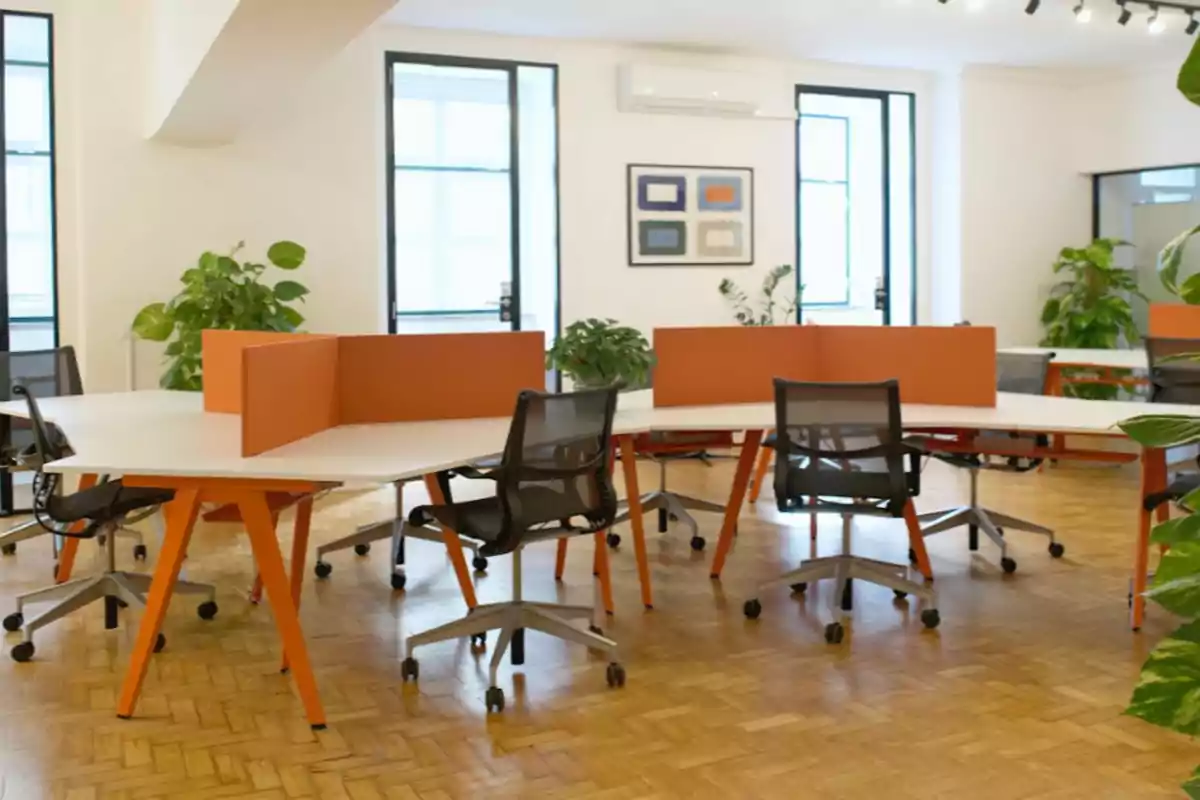 Oficina moderna con escritorios compartidos, sillas ergonómicas, divisores naranjas y plantas decorativas Oficina moderna con escritorios compartidos, sillas ergonómicas, divisores naranjas y plantas decorativas