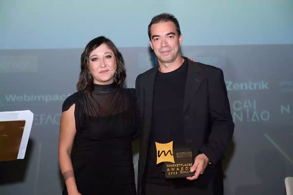 Dos personas posan sonrientes en un evento de premiación, una de ellas sostiene un trofeo que dice Marketplaces Award 2023 Spain. Dos personas posan sonrientes en un evento de premiación, una de ellas sostiene un trofeo que dice Marketplaces Award 2023 Spain.