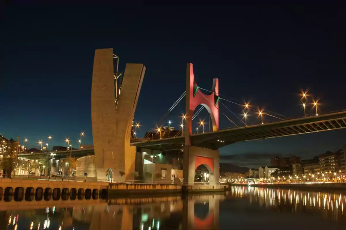 Puente moderno iluminado sobre un río en una ciudad durante la noche Puente moderno iluminado sobre un río en una ciudad durante la noche