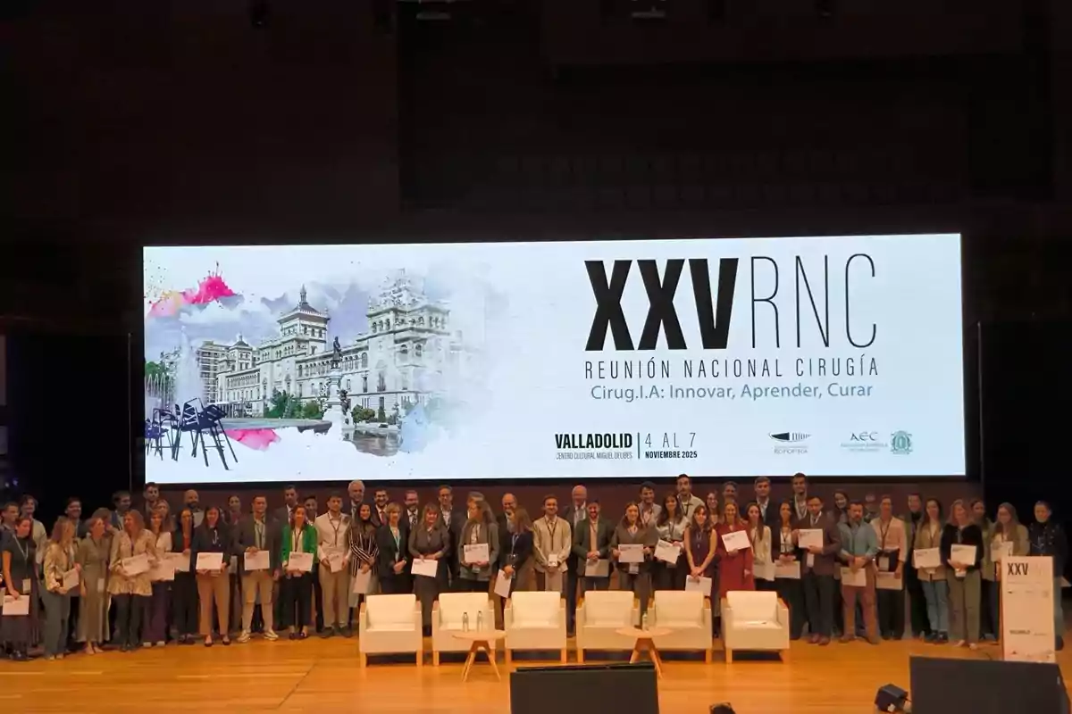 Grupo de personas posando en un escenario durante la XXV Reunión Nacional de Cirugía con un cartel de fondo que anuncia el evento en Valladolid en noviembre de 2025 Grupo de personas posando en un escenario durante la XXV Reunión Nacional de Cirugía con un cartel de fondo que anuncia el evento en Valladolid en noviembre de 2025
