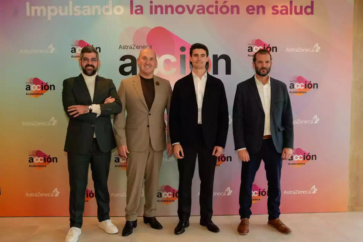 Cuatro hombres posan frente a un fondo colorido con logotipos de AstraZeneca y el texto impulsando la innovación en salud