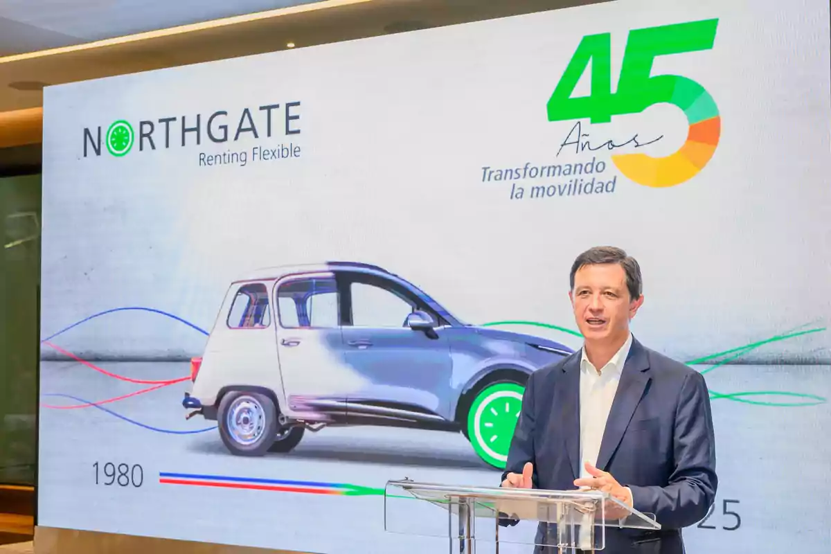 Hombre de traje hablando en un podio frente a una pantalla que muestra el logo de Northgate, un automóvil y el texto 45 años transformando la movilidad Hombre de traje hablando en un podio frente a una pantalla que muestra el logo de Northgate, un automóvil y el texto 45 años transformando la movilidad