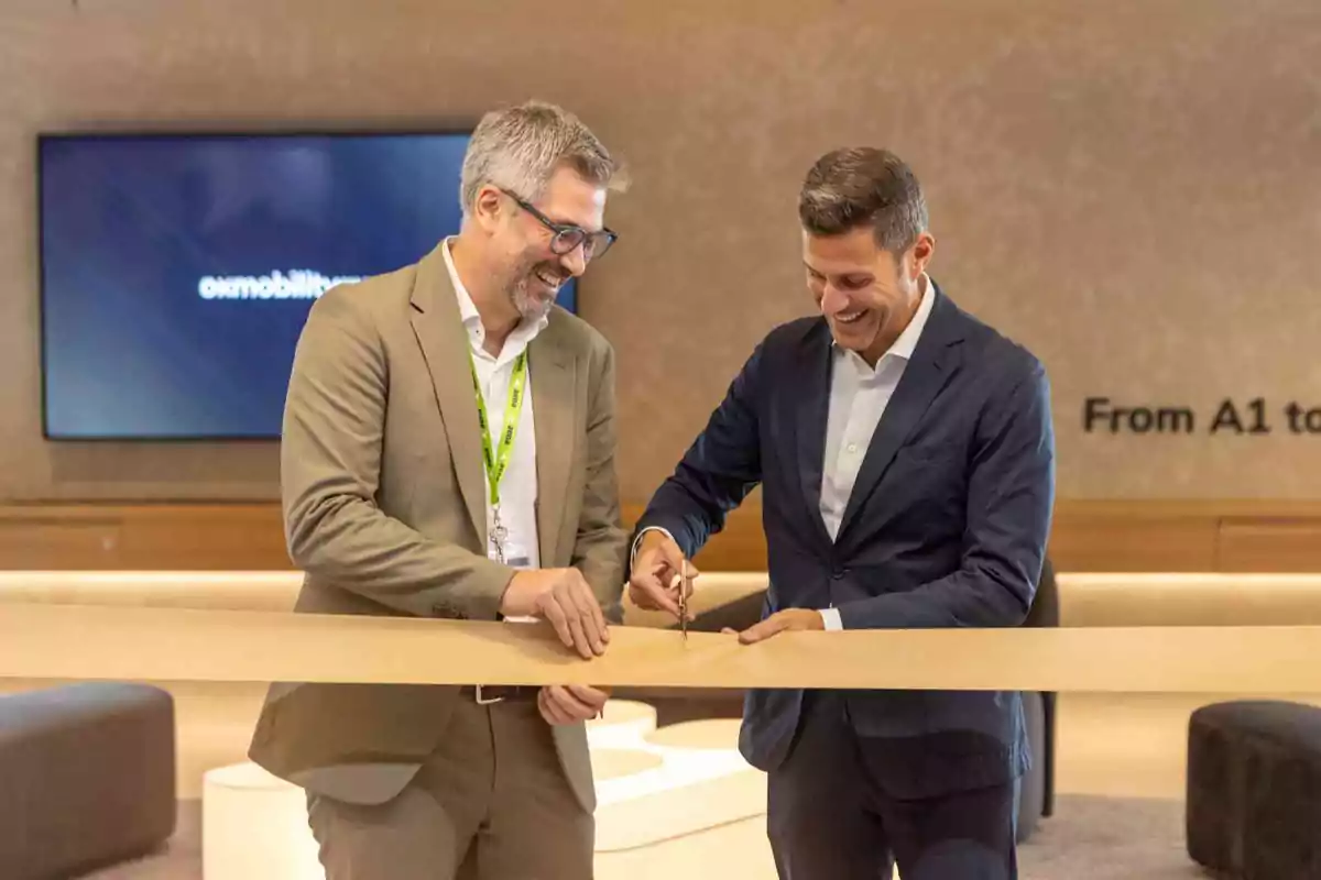 Dos hombres sonrientes cortan una cinta en una ceremonia de inauguración en un entorno moderno y profesional