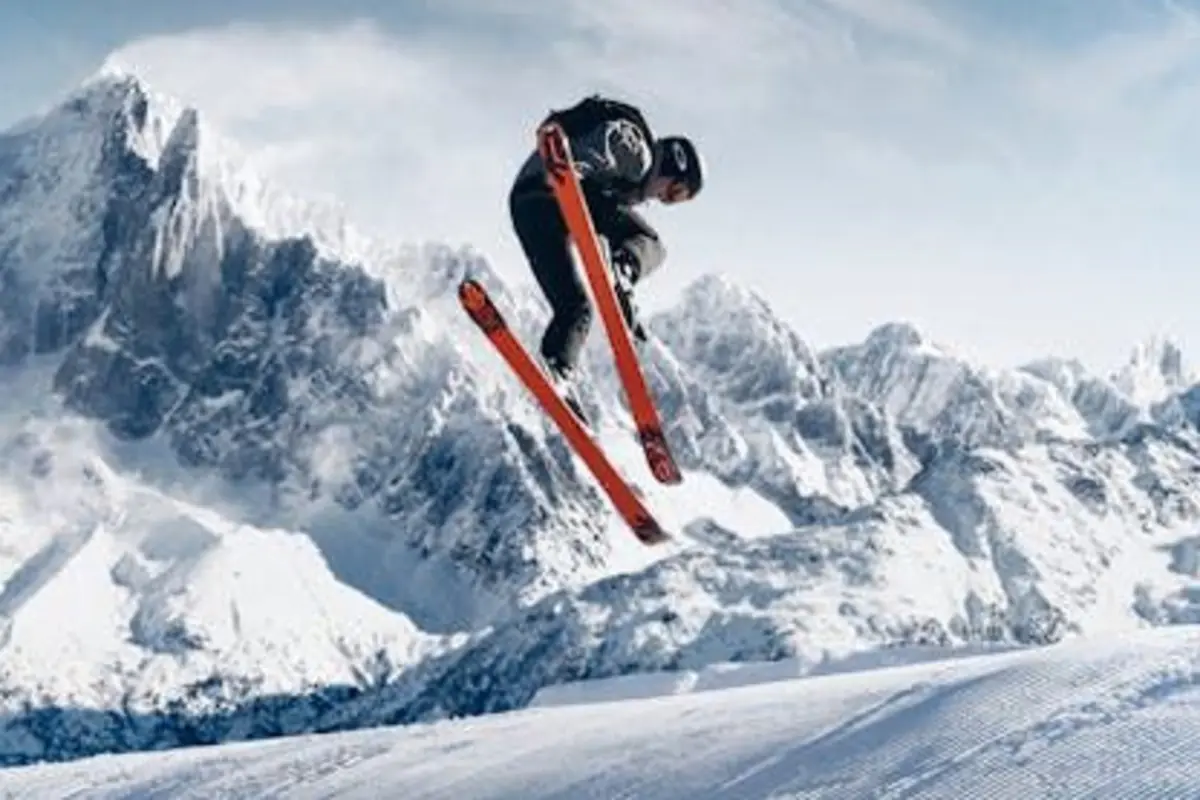 Persona esquiando y saltando en el aire con montañas nevadas al fondo