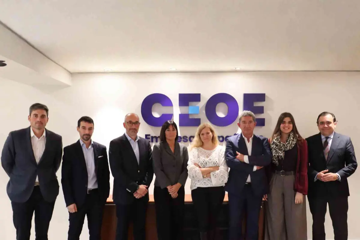 Ocho personas posan de pie en una oficina frente a un letrero de CEOE