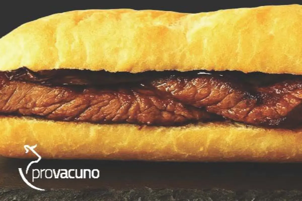 Bocadillo de pan crujiente relleno de carne asada con el logo de Provacuno en la esquina inferior izquierda Bocadillo de pan crujiente relleno de carne asada con el logo de Provacuno en la esquina inferior izquierda