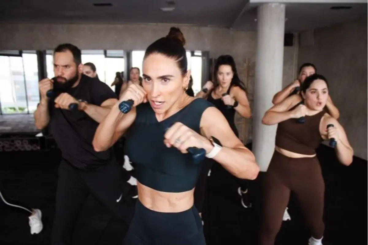 Grupo de personas haciendo ejercicio con pesas pequeñas en una clase de fitness en interiores