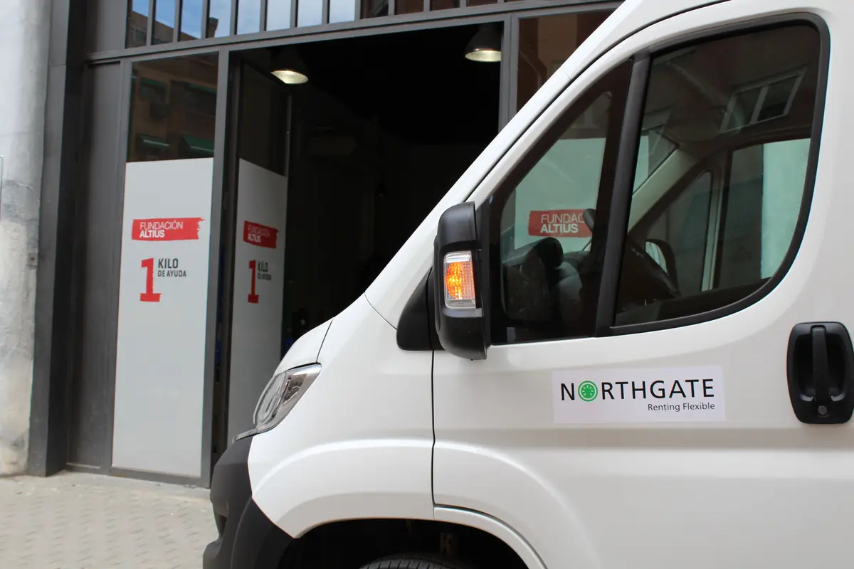 Furgoneta blanca de Northgate estacionada frente a la entrada de la Fundación Altius con carteles de la campaña 1 kilo de ayuda