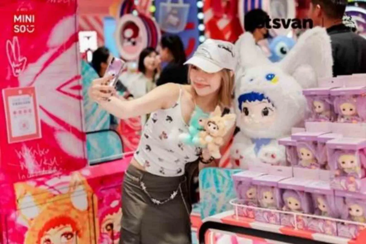 Joven tomándose una selfie en una tienda colorida de juguetes y peluches rodeada de muñecas en cajas y un gran peluche blanco Joven tomándose una selfie en una tienda colorida de juguetes y peluches rodeada de muñecas en cajas y un gran peluche blanco