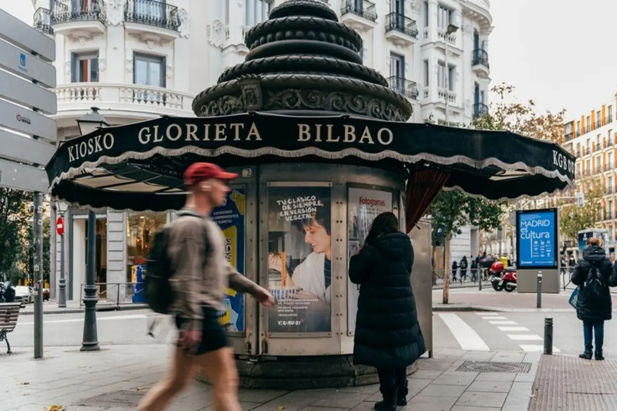 Kiosco circular de la Glorieta de Bilbao en una calle de Madrid con personas caminando y edificios clásicos al fondo