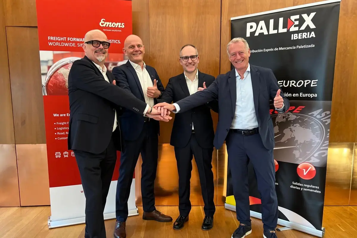 Cuatro ejecutivos de empresas de logística posan sonrientes con las manos unidas frente a roll ups corporativos de Emons y Pallex Iberia