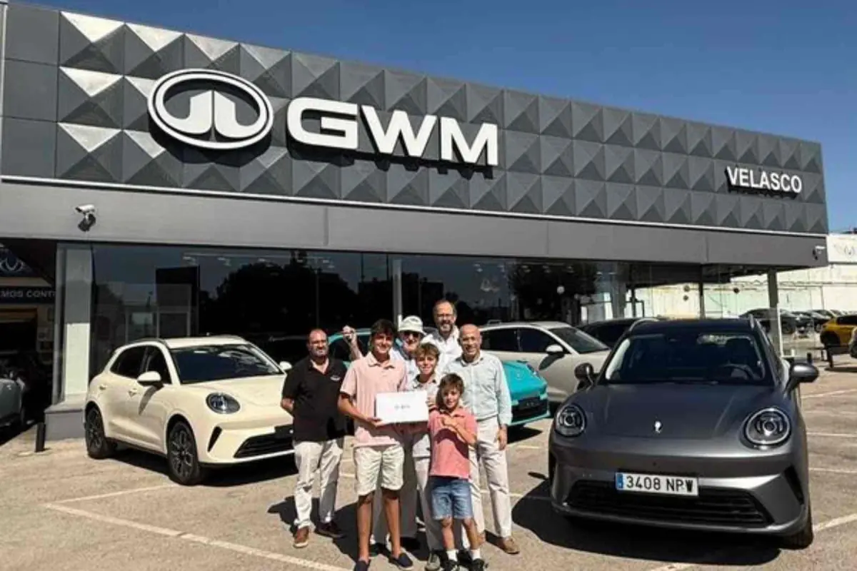 Grupo de personas posando frente a un concesionario GWM Velasco con varios coches nuevos aparcados en la entrada