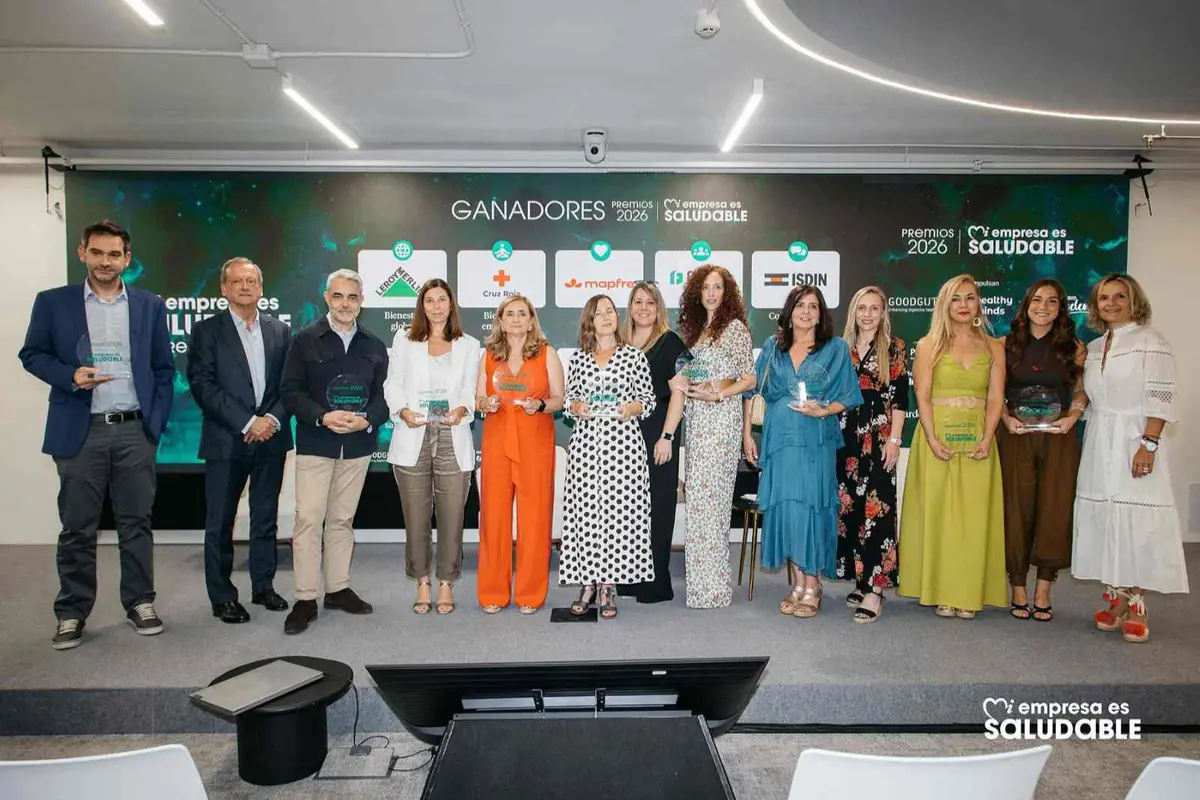 Grupo de personas en un escenario posando con trofeos durante una ceremonia de premios a empresas saludables con un gran cartel de ganadores de fondo