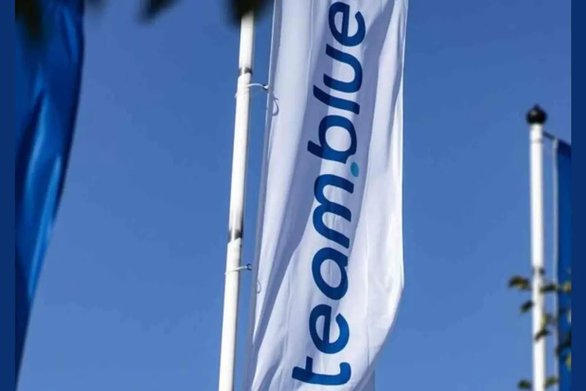Bandera blanca con el logo azul de team.blue ondeando sobre un cielo despejado