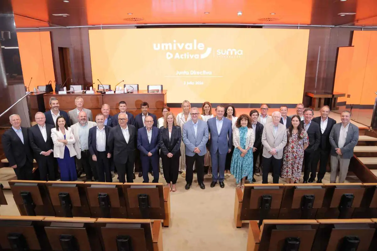 Grupo de directivos posando en un auditorio frente a una gran pantalla naranja con el logotipo de umivale Activa y suma y el texto Junta Directiva 3 julio 2024