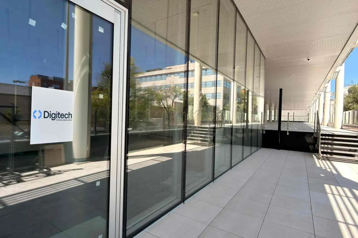 Entrada acristalada de oficinas modernas con cartel de la empresa Digitech en la puerta