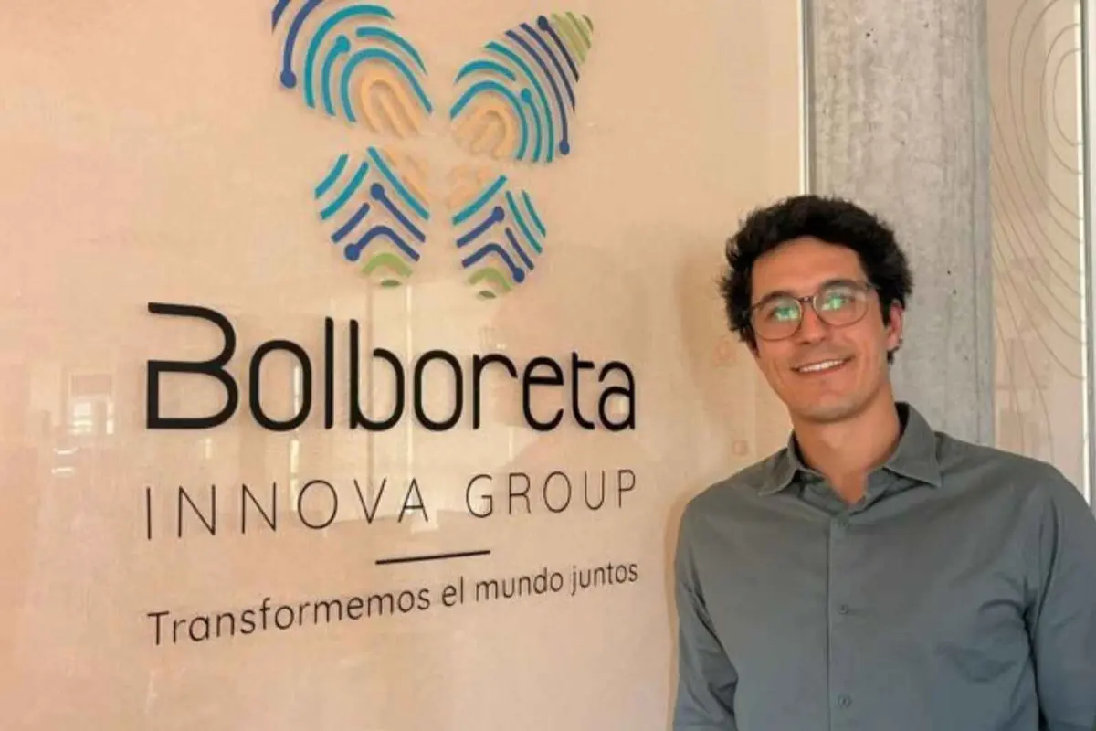 Hombre con camisa gris y gafas sonriendo junto a un cartel de Bolboreta Innova Group con el lema Transformemos el mundo juntos