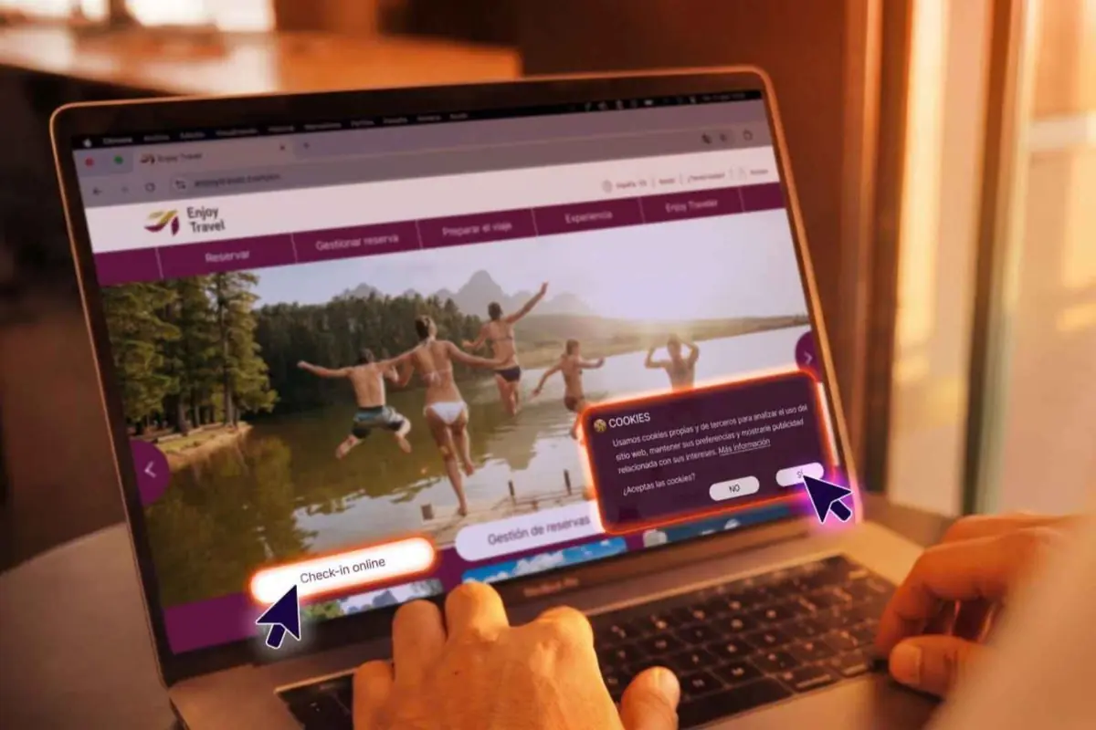Persona usando un portátil con una web de viajes abierta donde se ve una foto de jóvenes saltando a un lago y un aviso de cookies con botones de aceptar o rechazar