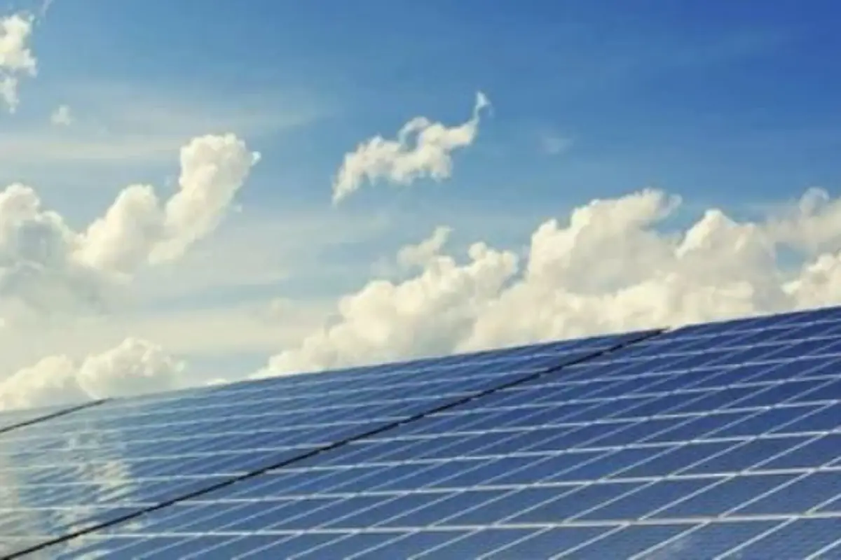 Paneles solares brillando bajo un cielo azul con nubes blancas