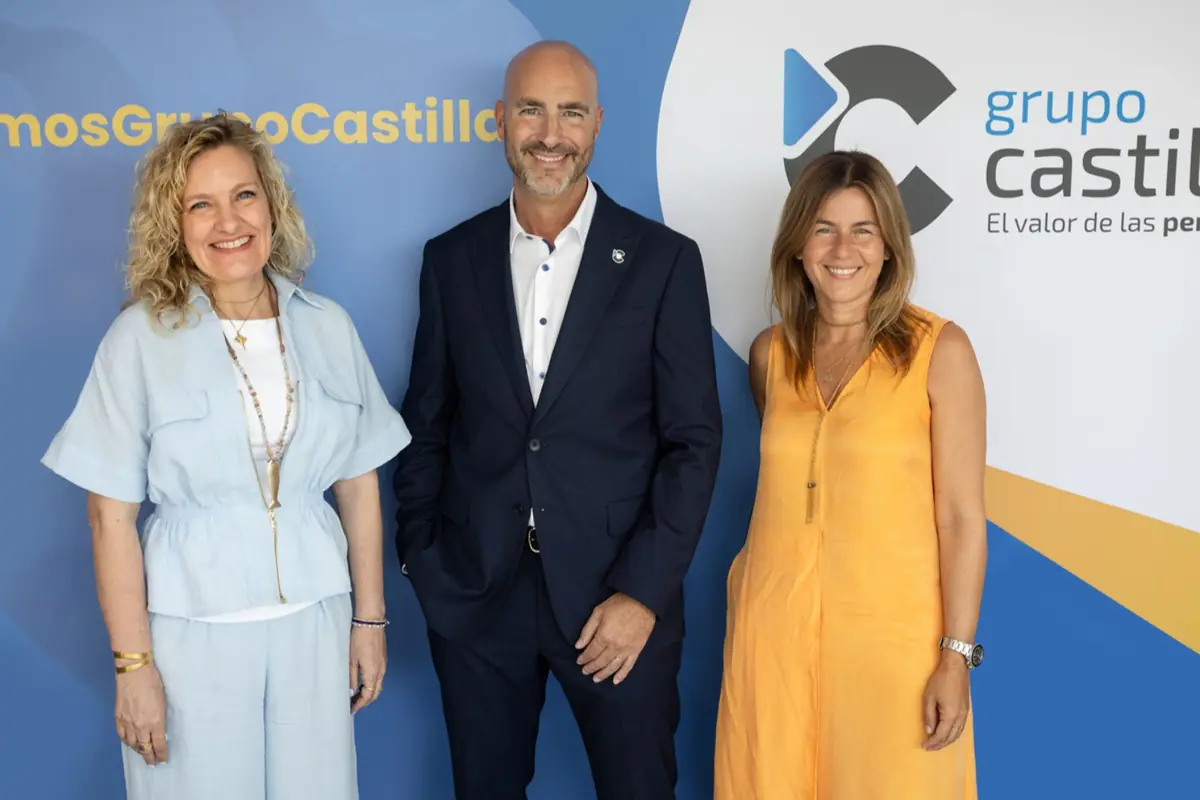 Tres personas sonriendo posan frente a un fondo corporativo de Grupo Castilla con el logotipo y el eslogan de la empresa visibles