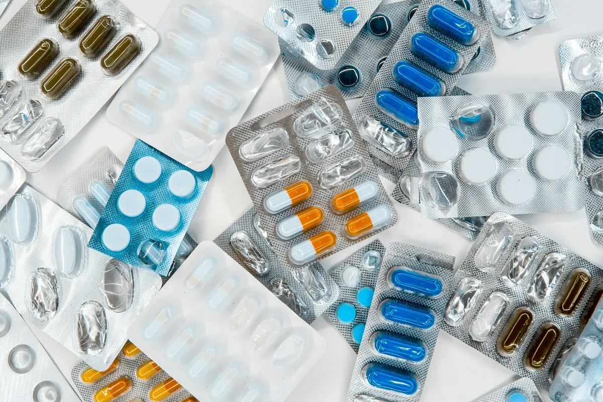 Blísters de diferentes pastillas y cápsulas de colores variados esparcidos sobre una superficie