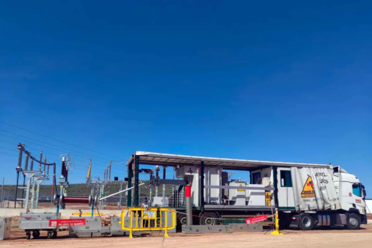 Camión equipado con transformador y maquinaria eléctrica estacionado en una subestación al aire libre bajo un cielo despejado
