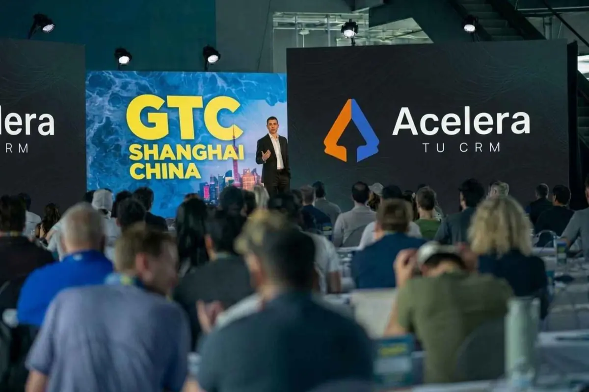 Conferencia de tecnología en un auditorio con un ponente en el escenario frente a dos grandes pantallas que muestran el texto GTC Shanghai China y el logotipo con la frase Acelera tu CRM mientras el público escucha sentado Conferencia de tecnología en un auditorio con un ponente en el escenario frente a dos grandes pantallas que muestran el texto GTC Shanghai China y el logotipo con la frase Acelera tu CRM mientras el público escucha sentado
