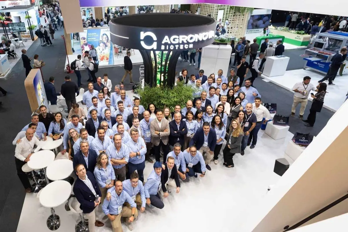 Gran grupo de personas posando sonriente en el stand de Agronova Biotech dentro de una feria o congreso empresarial