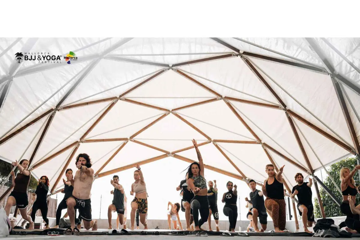 Grupo de personas practicando yoga en un gran domo geométrico durante el Mallorca BJJ and Yoga Festival