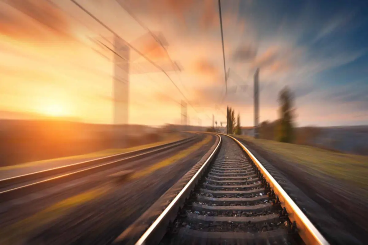 Vías de tren curvas al atardecer con efecto de movimiento y cielo anaranjado