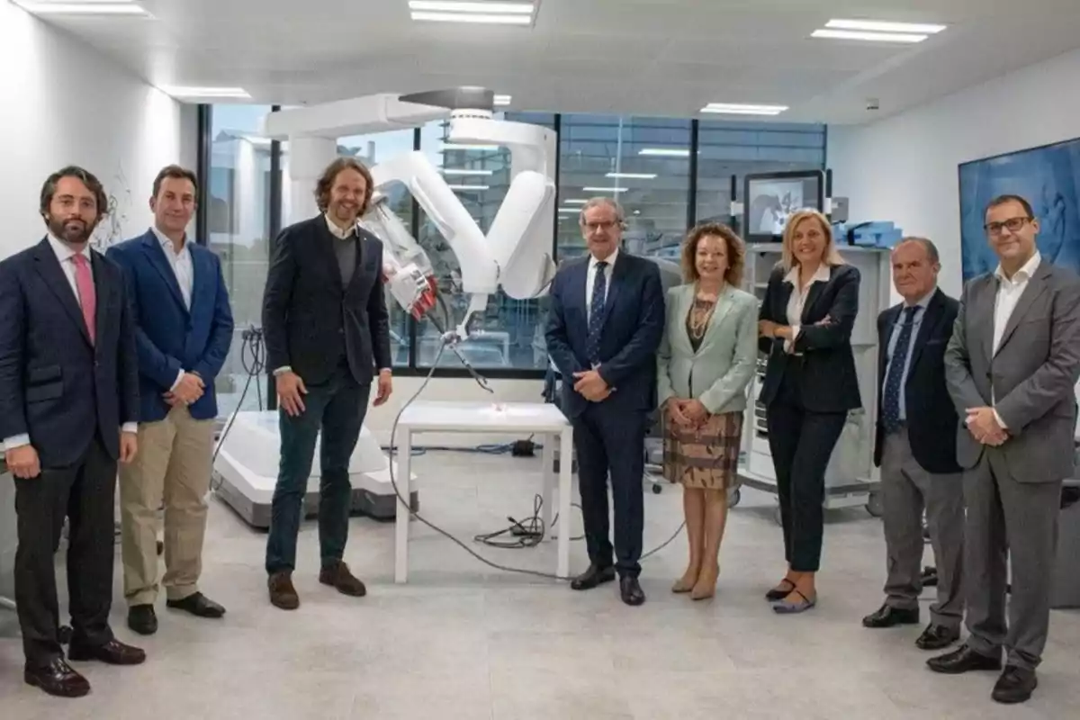 Un grupo de personas posando en una sala con un robot médico en el fondo.